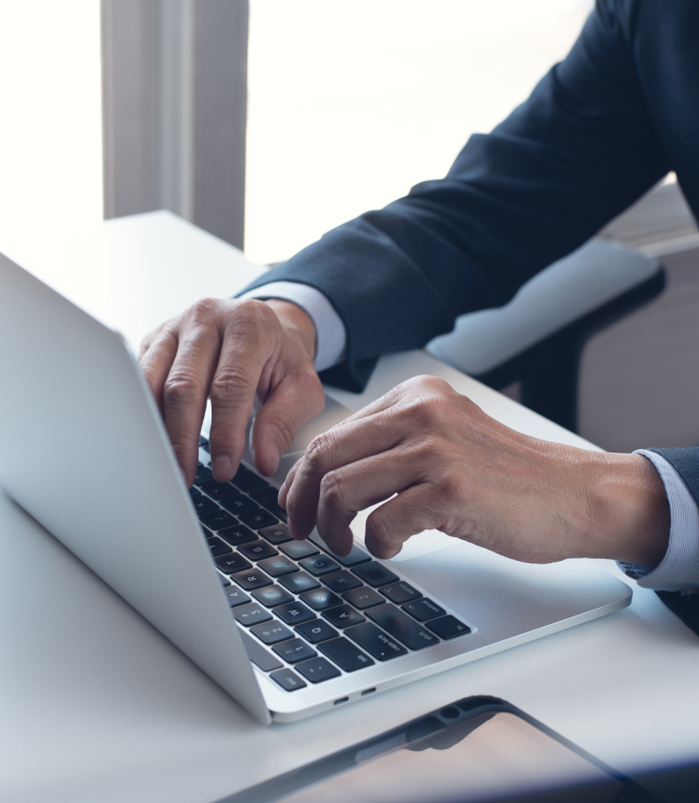Close up of man in suit typing on laptop